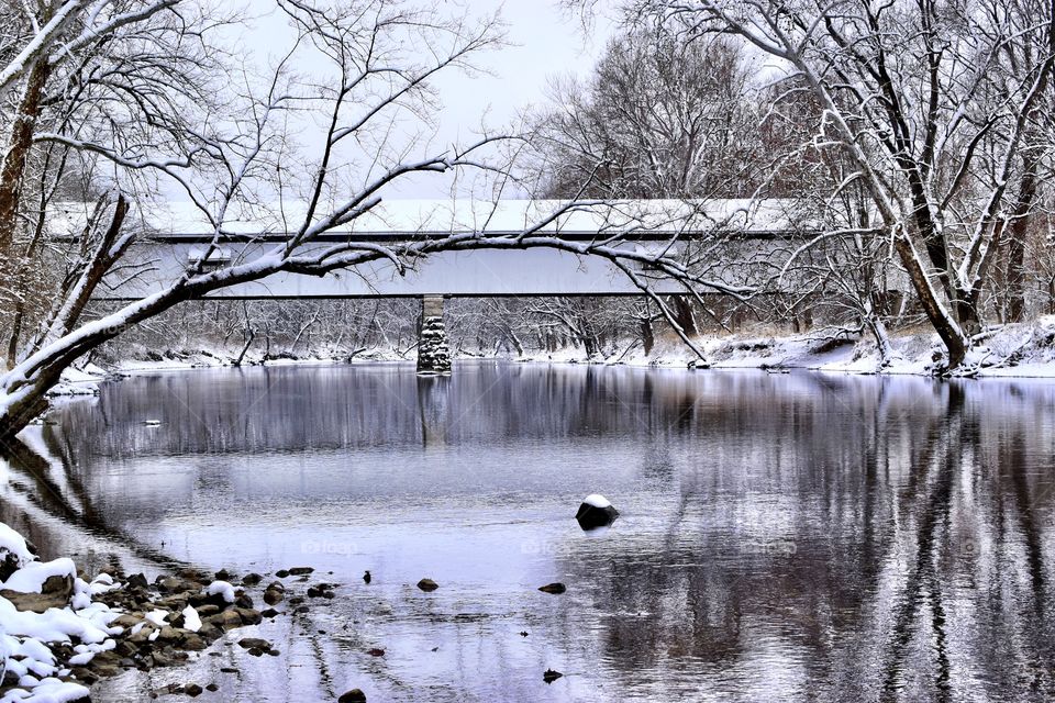 Winter after a snow in Indiana on the white river with the old covered bridge with a reflection on the water 