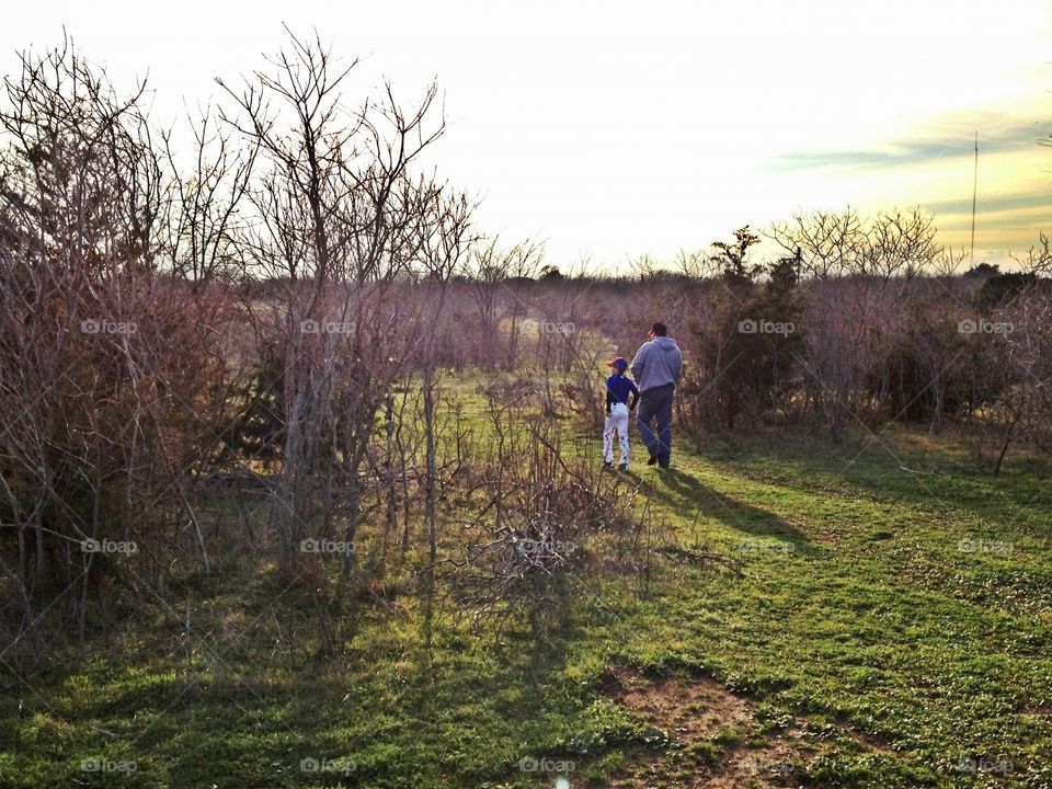 Father and son walking through the woods - after a baseball game. 