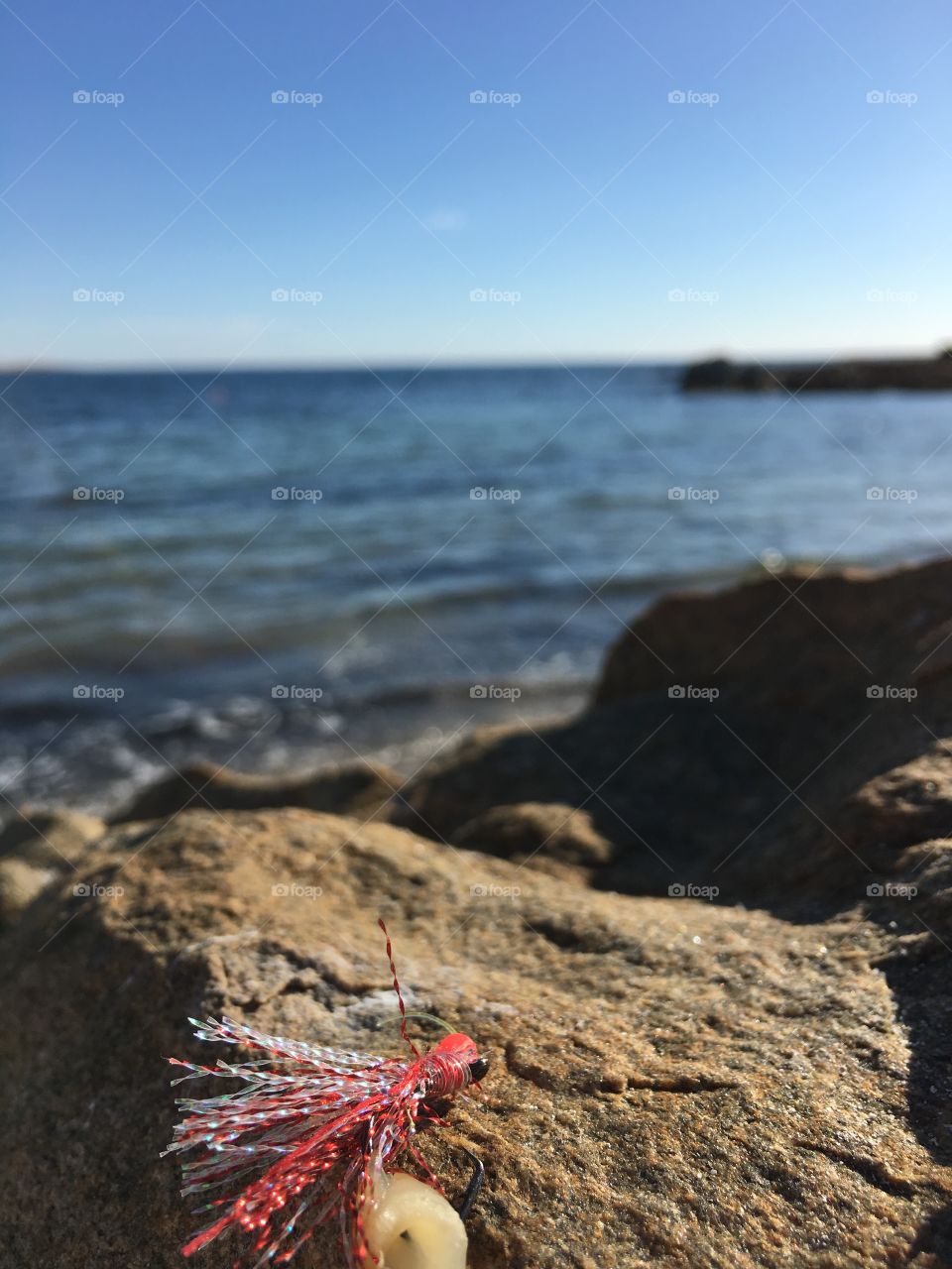 A remote fishing spot, off the rocks on a pristine beach, here a view with a fishing fly in the foreground, ocean, sky, island, background south Australia 