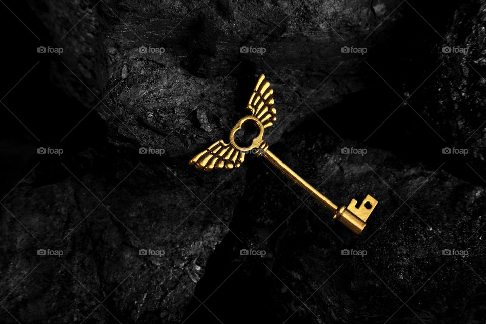 Golden antique key with wings on dark background