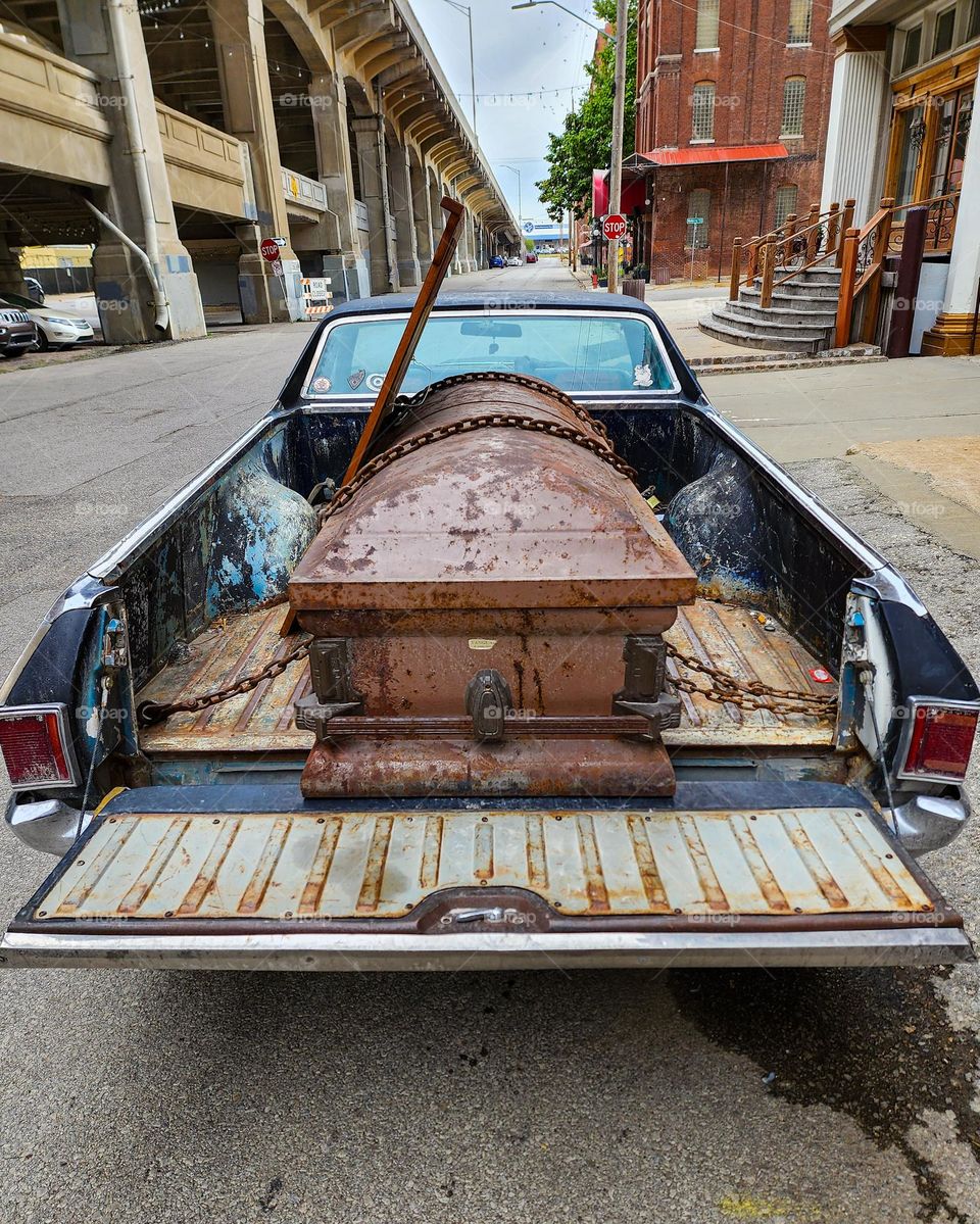 A vehicle has its tailgate lowered in order to accommodate the large casket in the bed