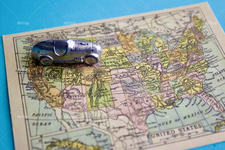 Miniature silver racer heading east on a miniature vintage map of the United States of America against a sky blue background