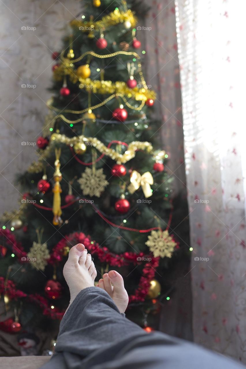 Female feet on the Christmas tree background 