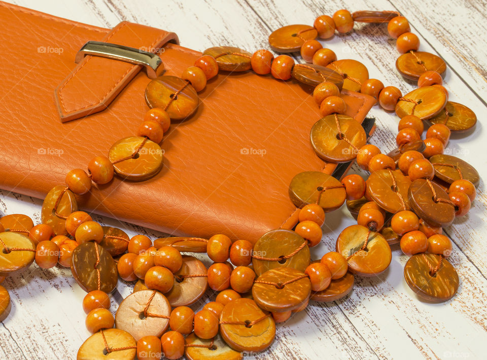 Orange leather wallet and string of wooden beads.