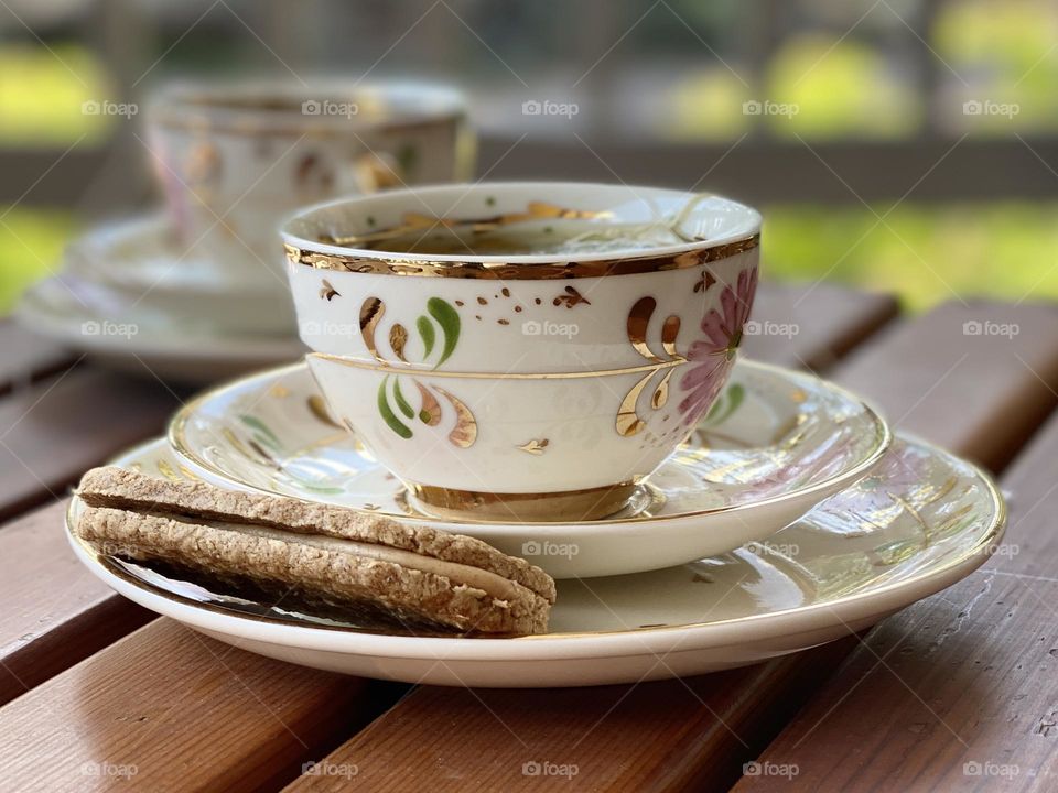 Centered cup of tea with biscuit outside on patio 