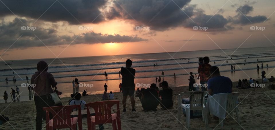 Sunset of Kuta Beach in Bali. All eyes look towards the sea and the beach.