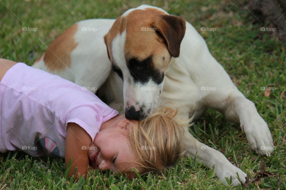 Daughter and her pet dog playing in the grass 