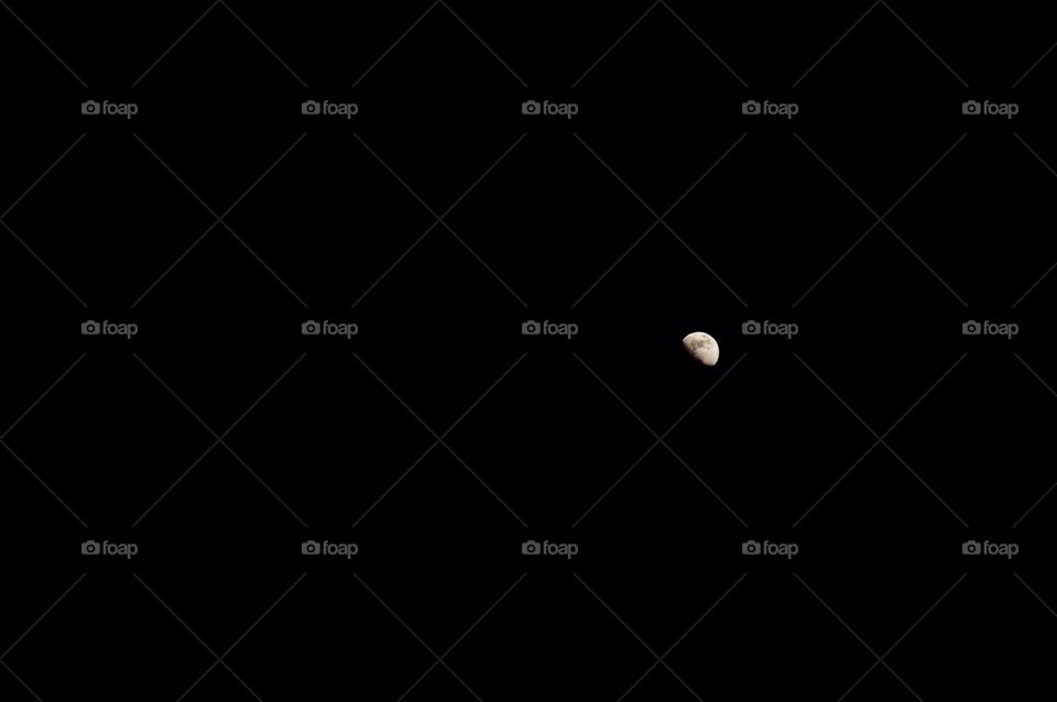 The half of the moon on the right side at night with black sky background. The small half of the moon. 