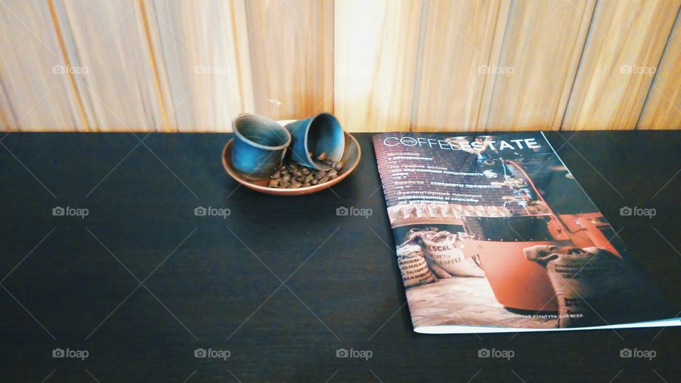 cups, coffee beans and a magazine on the table