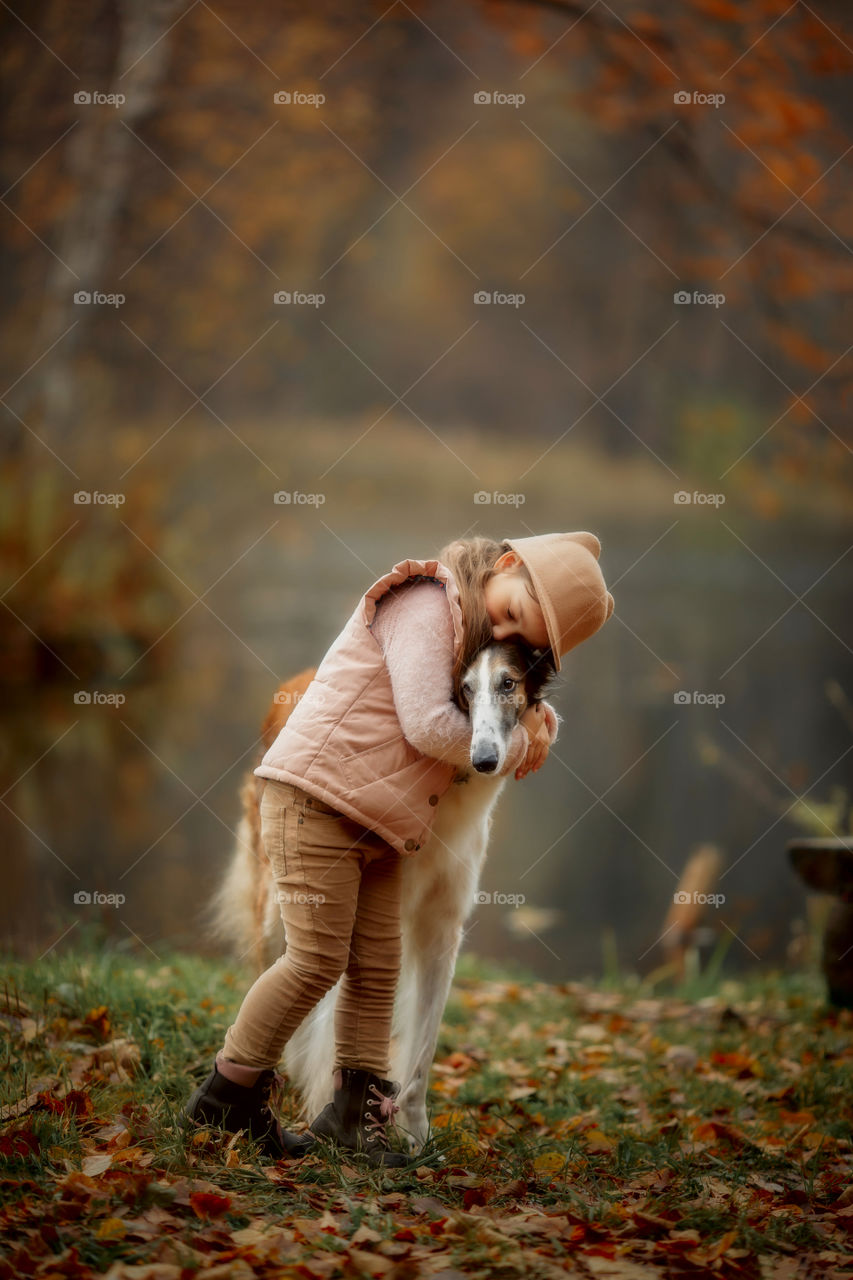 Cute smiling girl with russian borzoi dog in an autumn park 