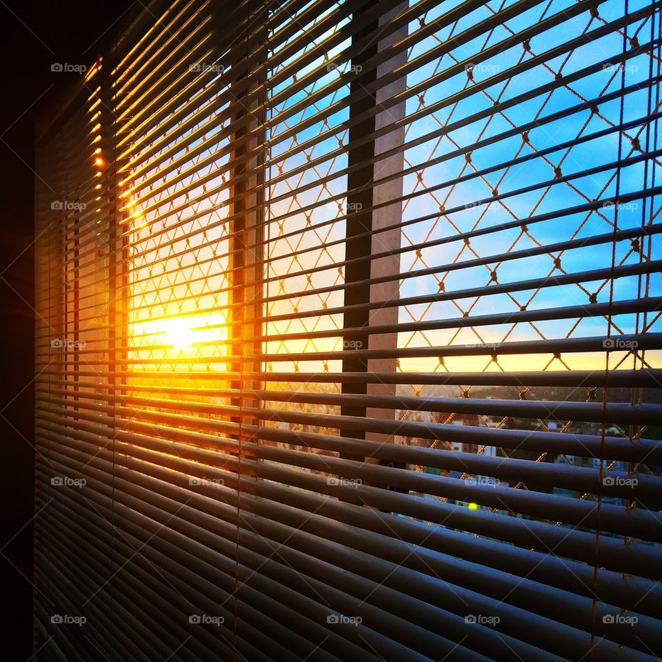 View of sunset through window blinds