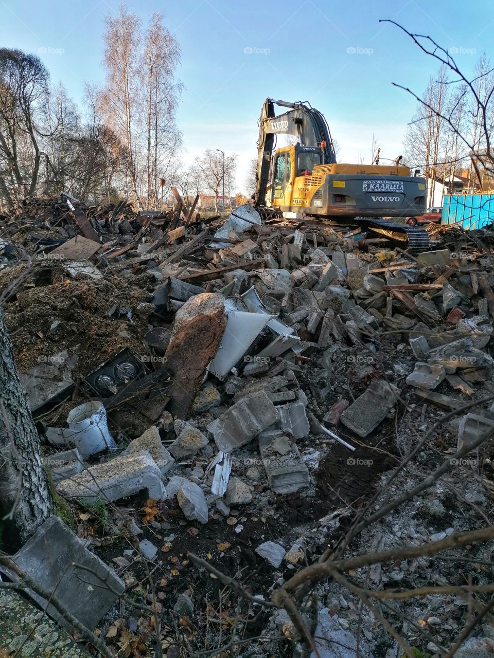 A firefighter and an excavator extinguishing a fire in a large building.