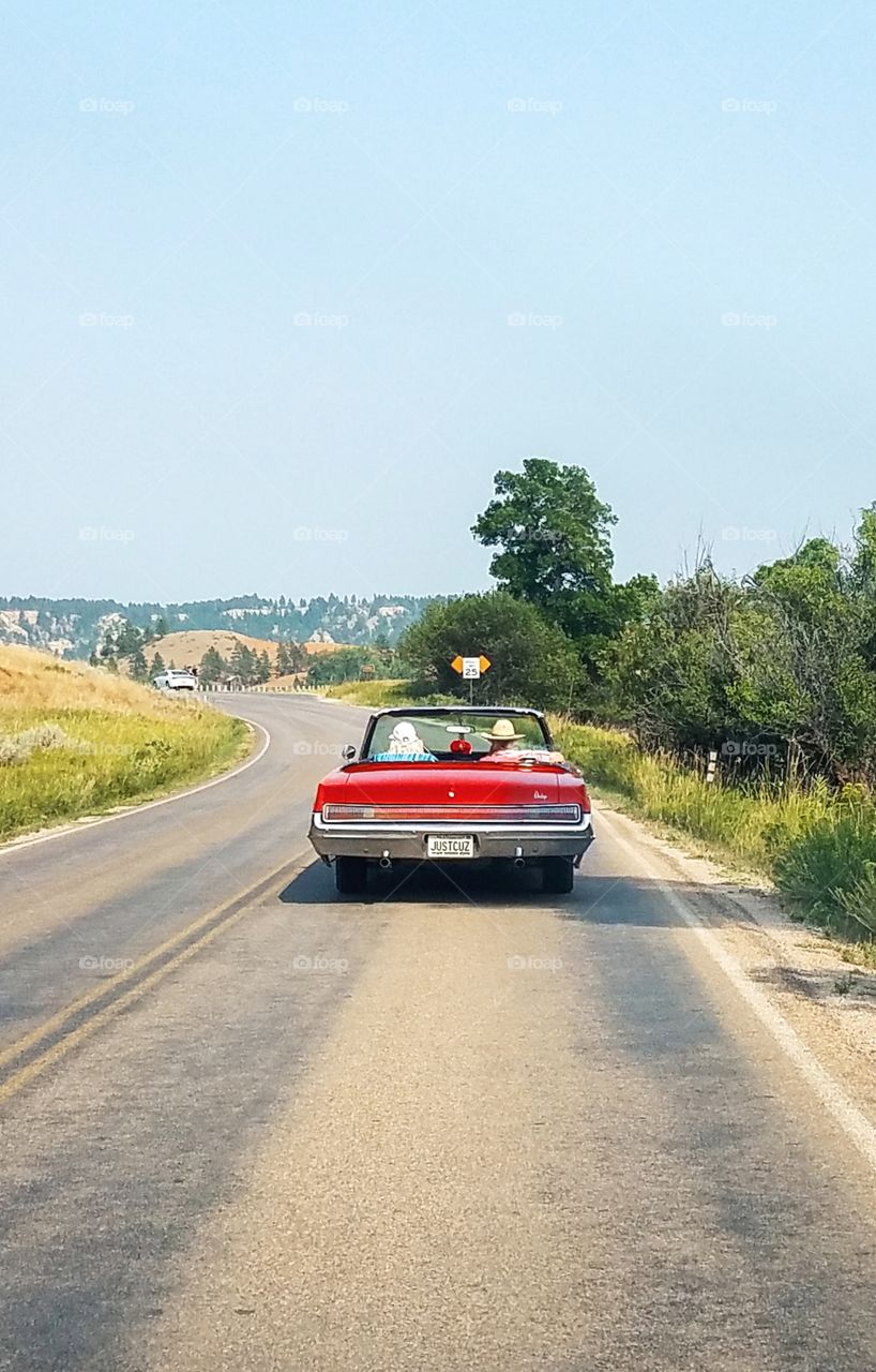 classic red car driving down a winding road.