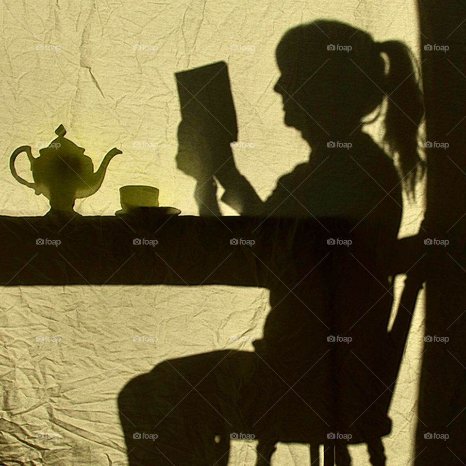 Daily routine, silhouette of a woman reading a book and having tea