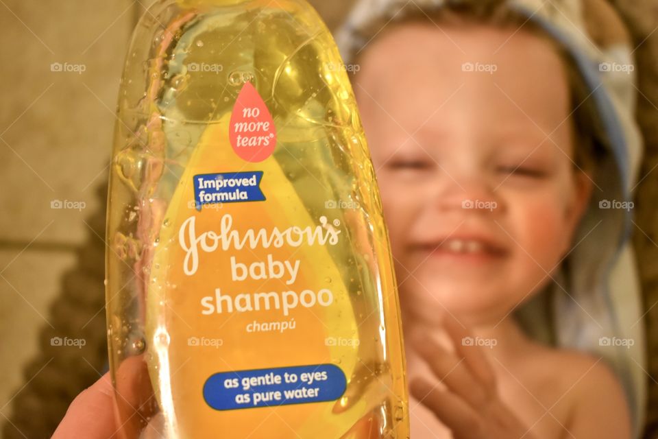 Cute toddler boy having fun in bath and washing his hair with Johnson’s baby shampoo 
