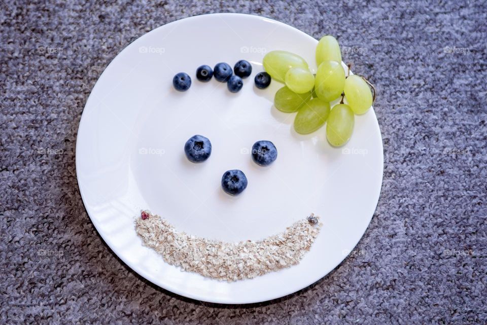 Fruits and berries on a white plate in the form of a smiley