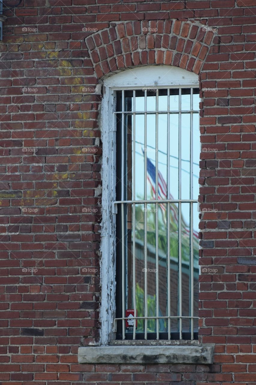 The U.S. Flag from the National Cemetery in Fort Smith,Arkansas, reflected in the window of an old downtown building