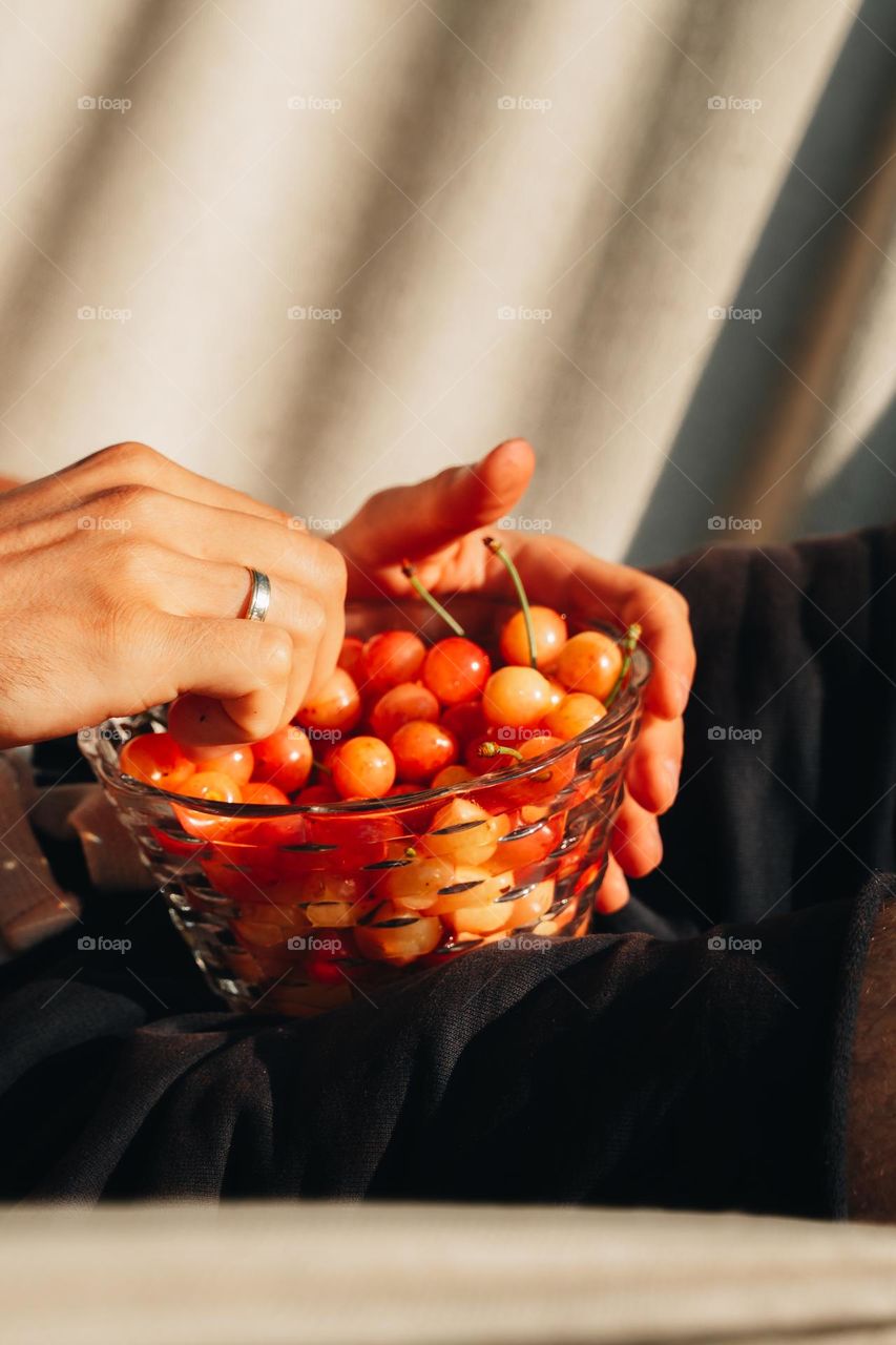 Man in hammock eating fresh ripe red cherries 