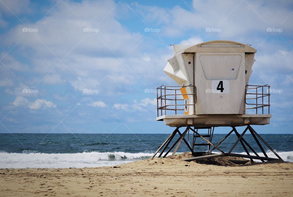 A lifeguard station is positioned near the waters edge at a beach in San Diego. Blue sky and waves in the background 