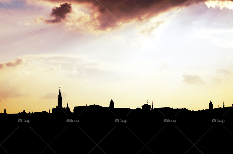 Silhouette of riverbank and cityscape in Budapest, Hungary during sunset.