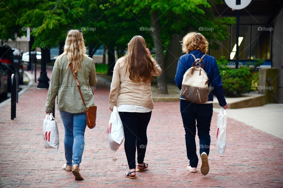 three girls carrying shopping bags walking down the street