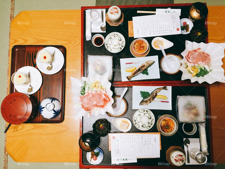 Top down view of set dinners for 2 at a ryokan (traditional Japanese style inn). Dinner is served in your room. 

(Note this photo all the lids and covers are still on) 