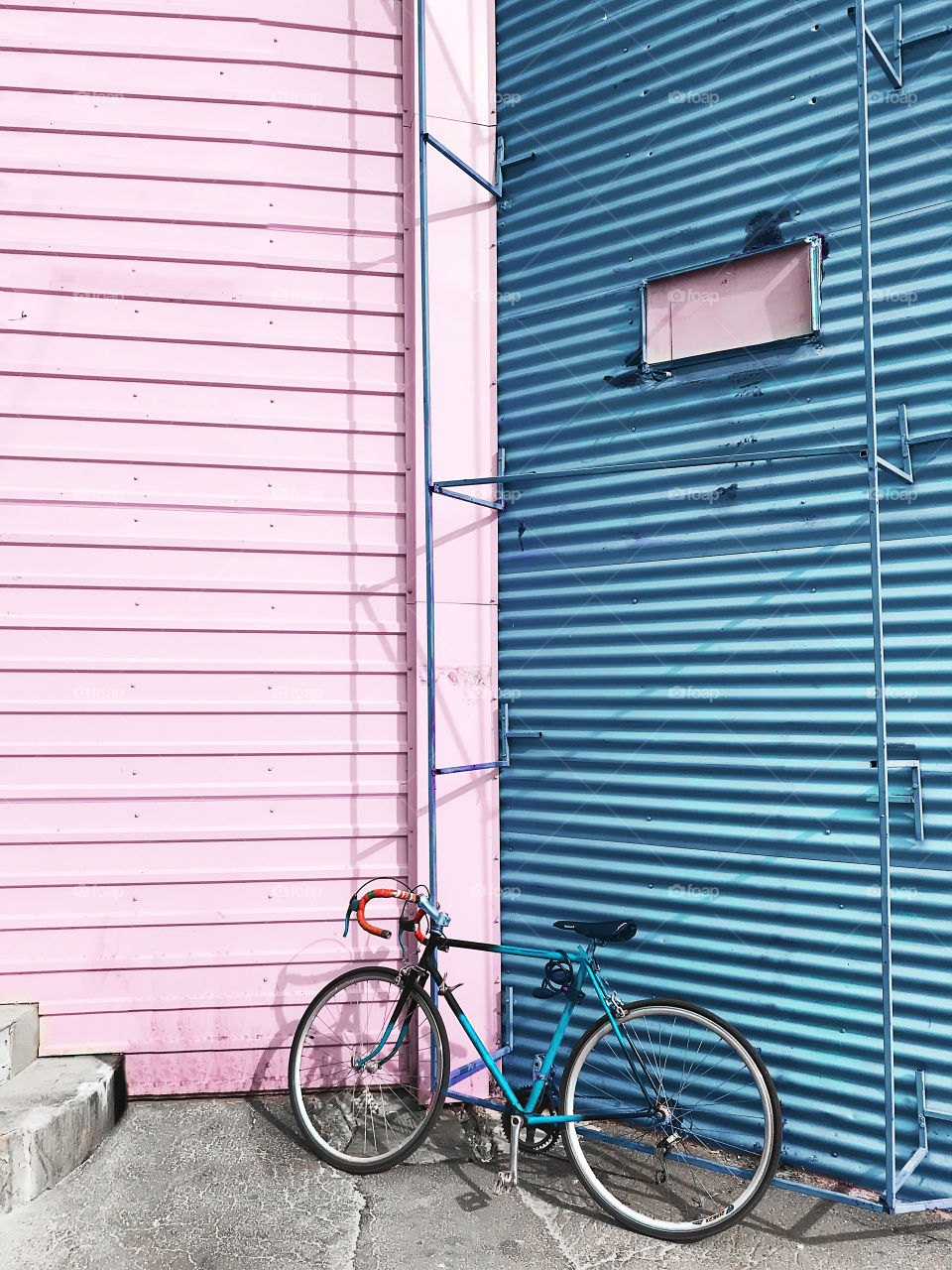 Bicycle standing in front of a blue and pink pastel wall 