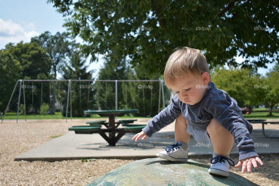 Cute baby boy climbing on playground toys