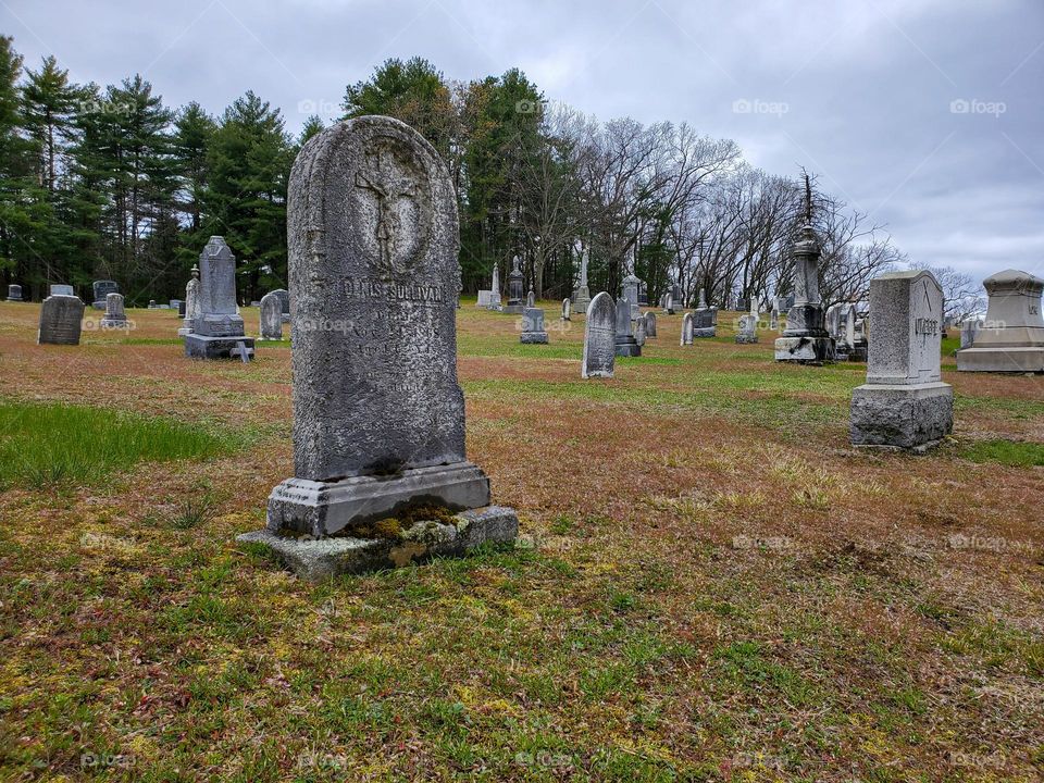 An old cemetery sits on a hillside and features many old headstones