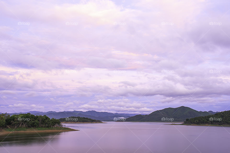 The reflection of the Sun and the clouds on the sky Background mountain and water at Kaeng Krachan dam in phetchaburi , Thailand.