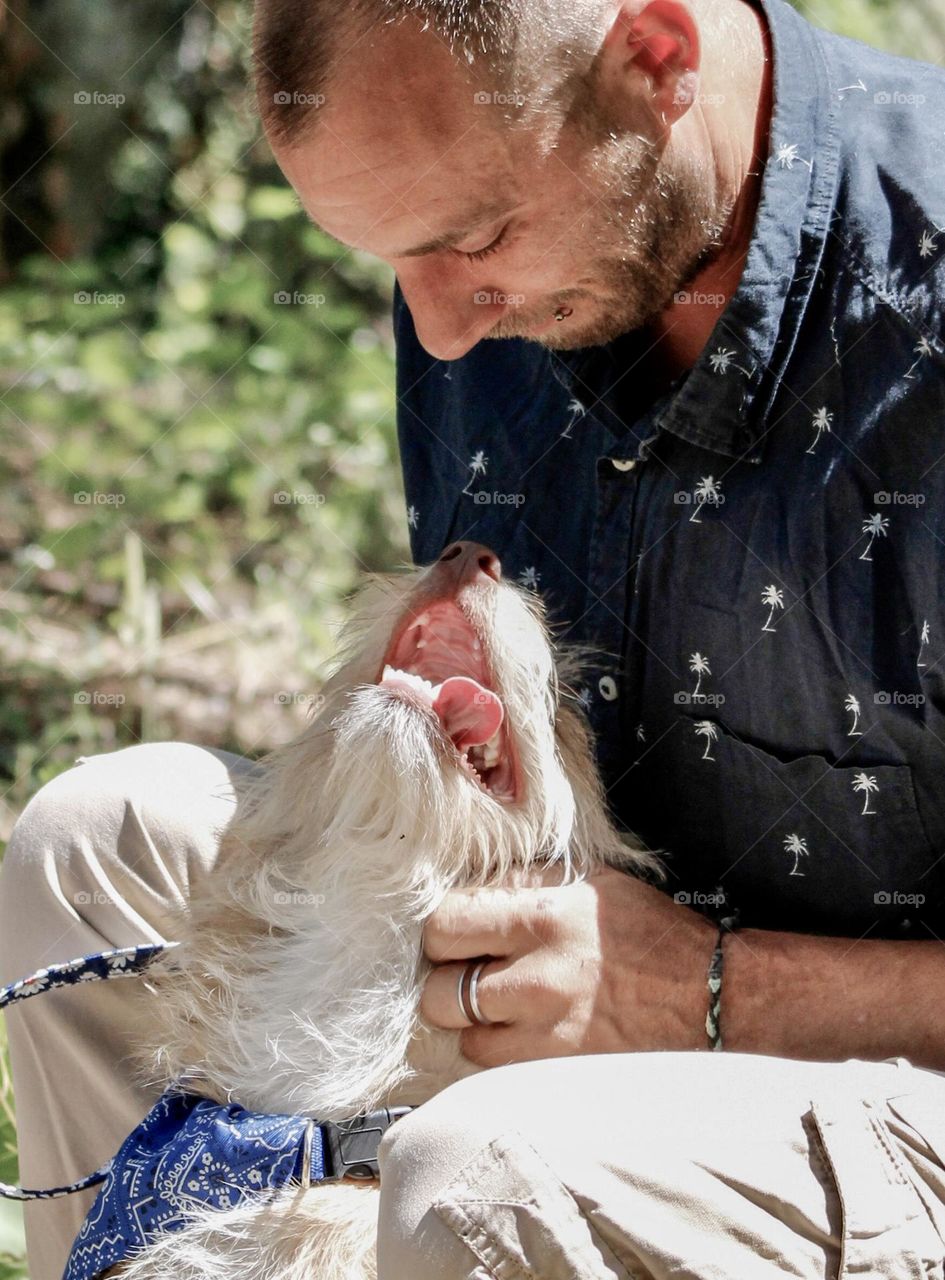 A man strokes his dog who is affectionately looking up at him