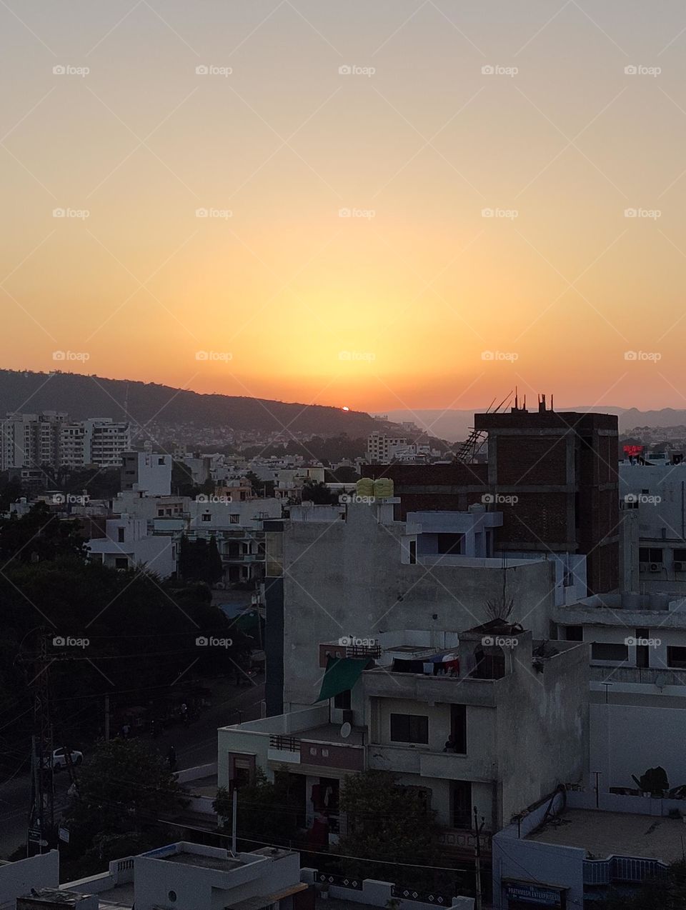 a sunset scene in evening time, small and big house, mountain view, yellow sky, sun