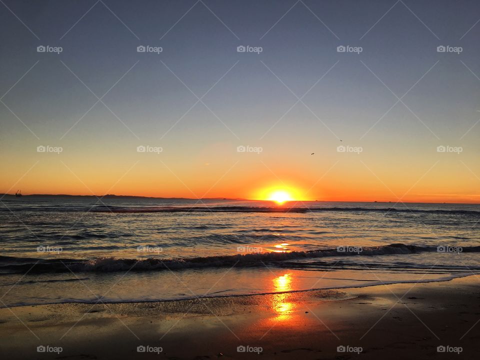 This photo captures the end of a beautiful sunset over the waves of a California ocean.