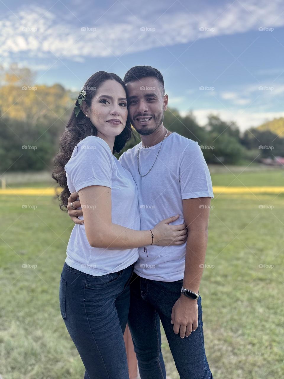 Young couple posing for a portrait on a beautiful and green landscape in a sunny day.