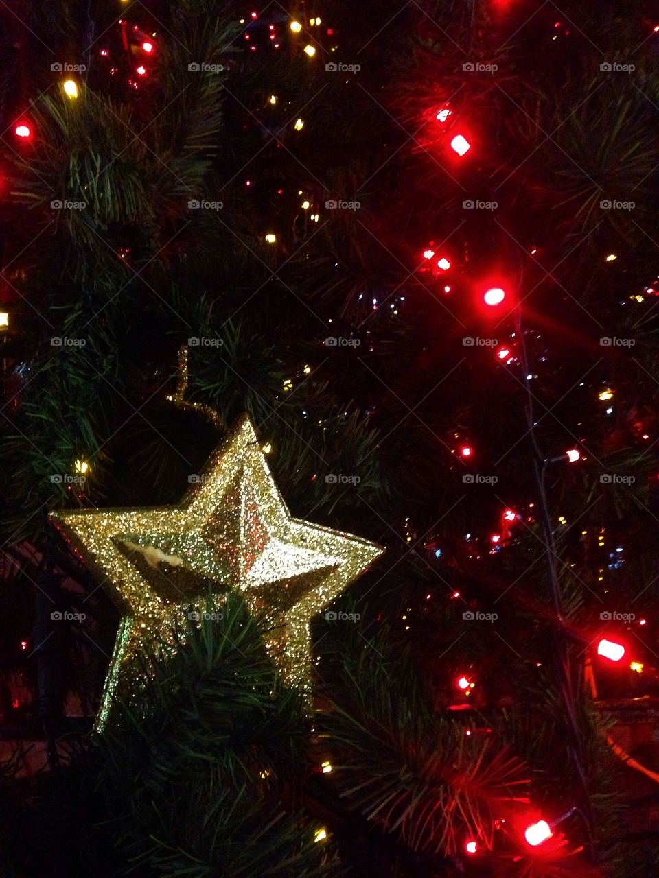 Gold plastic star, balls, red lights garland and other Christmas decorations on artificial fir tree in Moscow, Russia