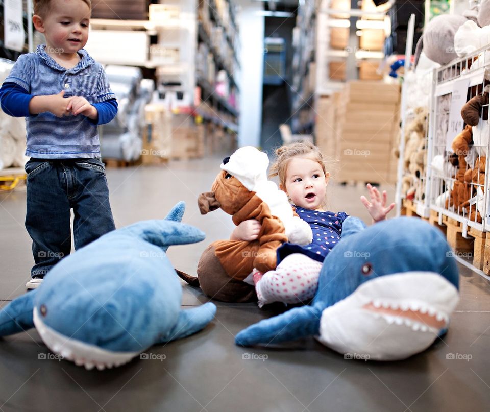 Little girl and boy playing with stuffed animals in a store 