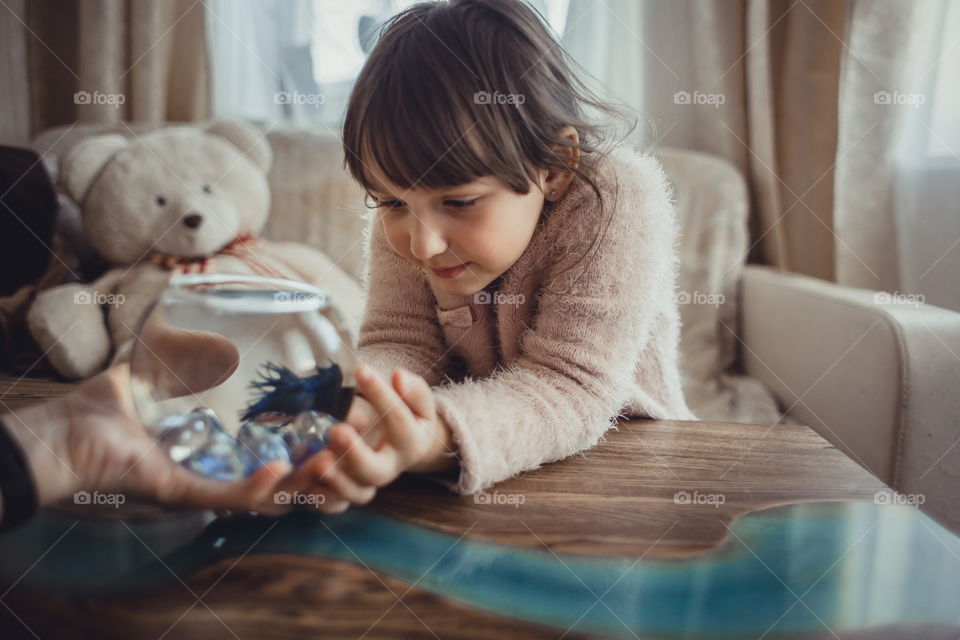 Girl with fish in round aquarium. 
