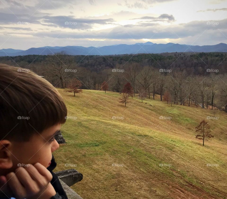 Boy surveying country side from loggia of Biltmore House; thoughtful, pensive 