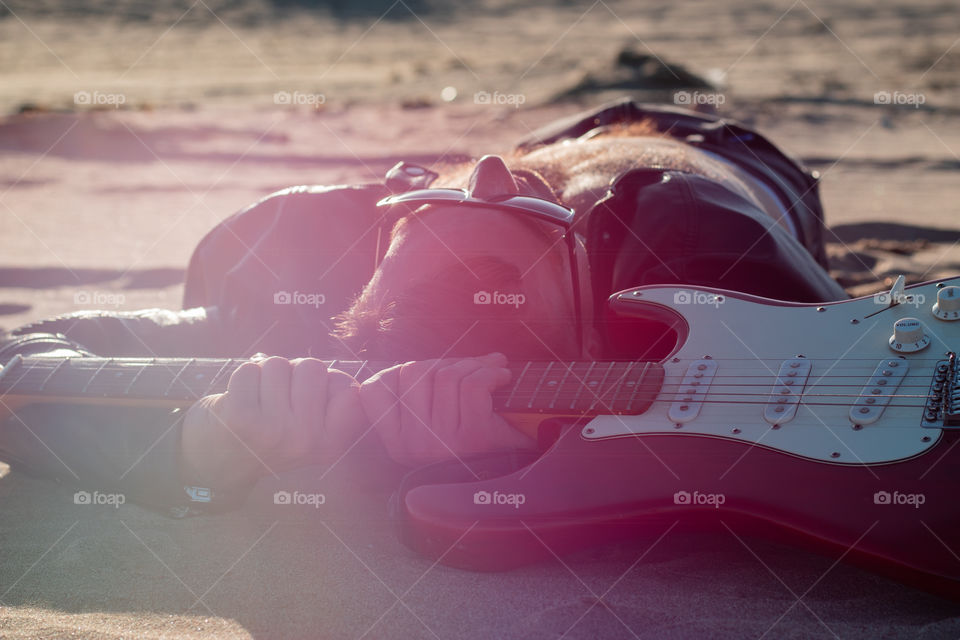 Musician relaxing on a beach and holding guitar