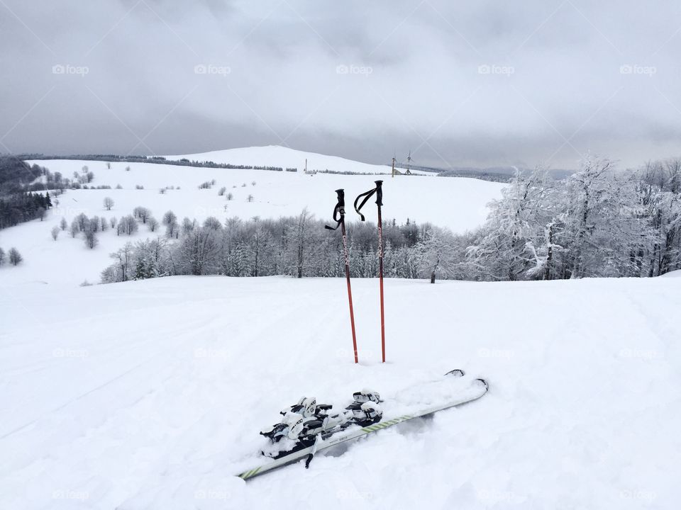 Skis in the snow with ski poles surrounded by winter scenery