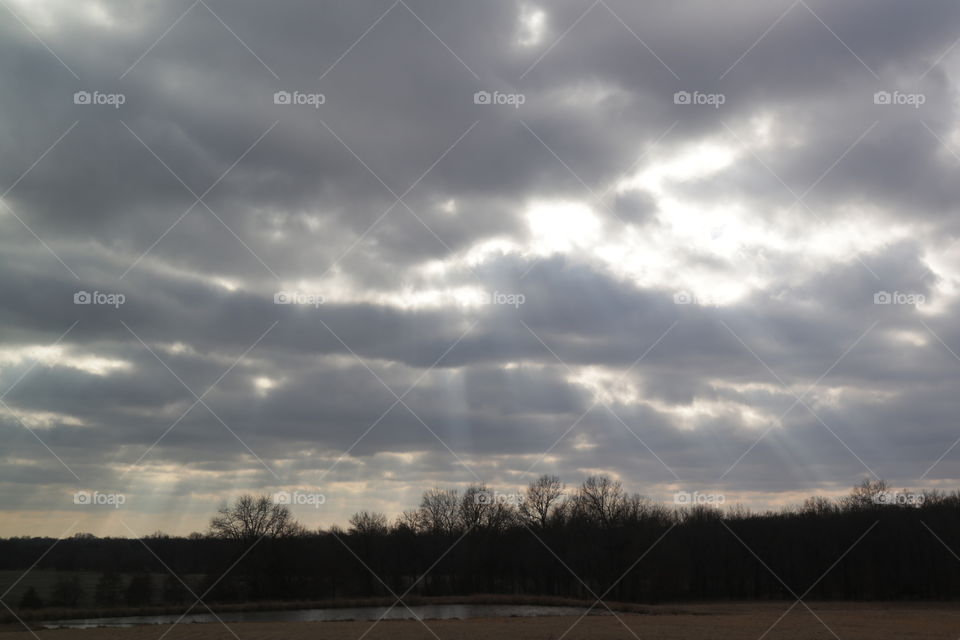 A grey cloudy day with the bright sun parking through the passing clouds.