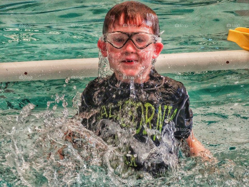 Young Boy Splashing in Pool