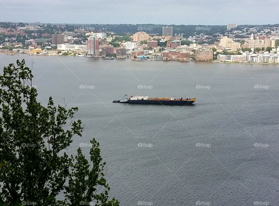 A tug boat pushes a barge along the Hudson river in the palisades.