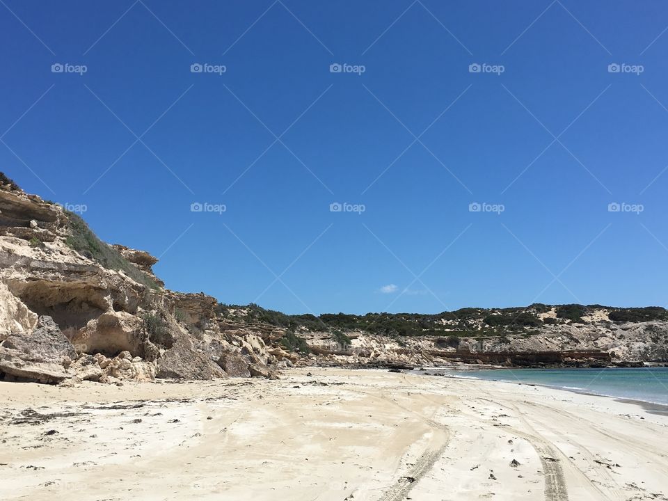 Sea cliffs flanking a remote white sand. Each with turquoise waters on clear blue summer day in south Australia 