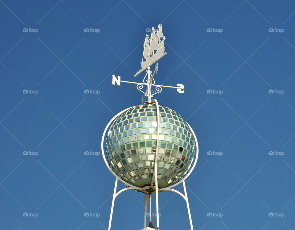 white rose of winds with a ship and mirror ball against dark blue sky in sunny summer day. Brighton pier UK