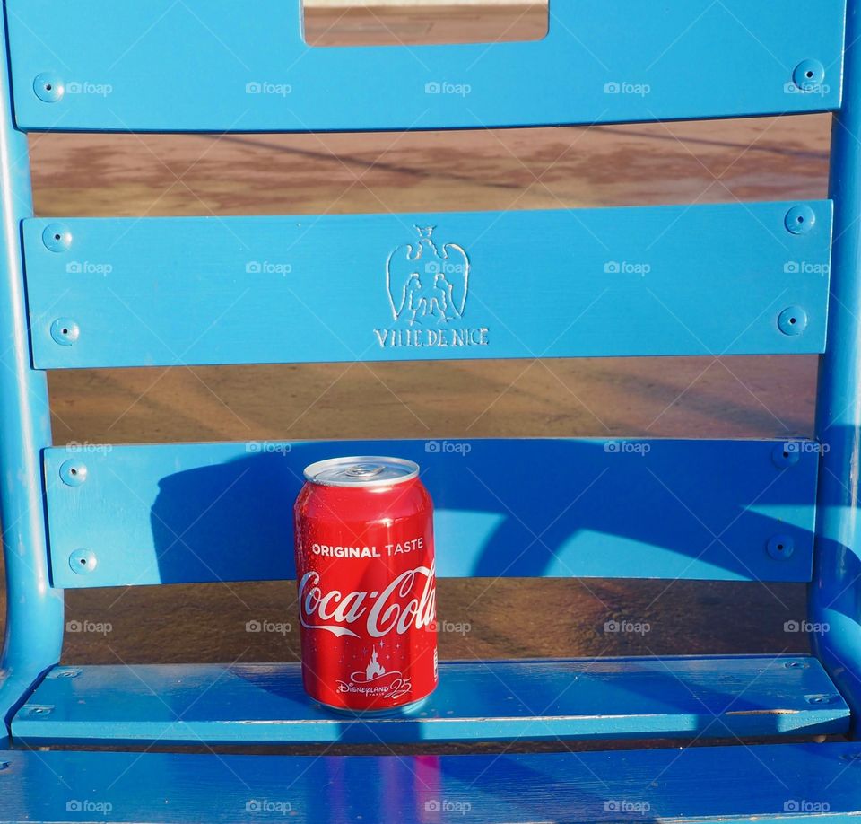 A can of Coca Cola on a blue chair in Nice, France.