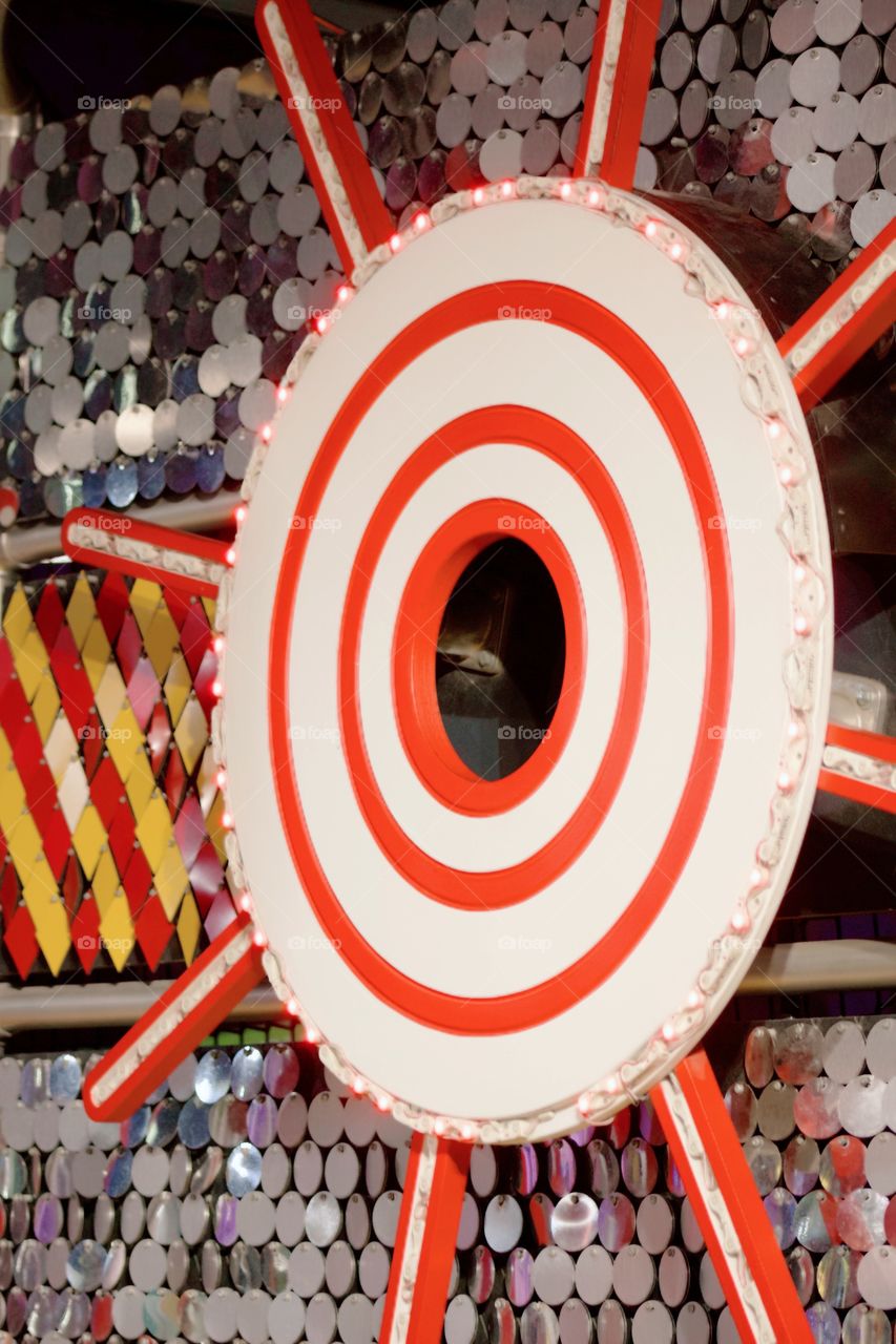 Lighted target with shiny background of metal discs and red and yellow diamond-shaped metal pieces