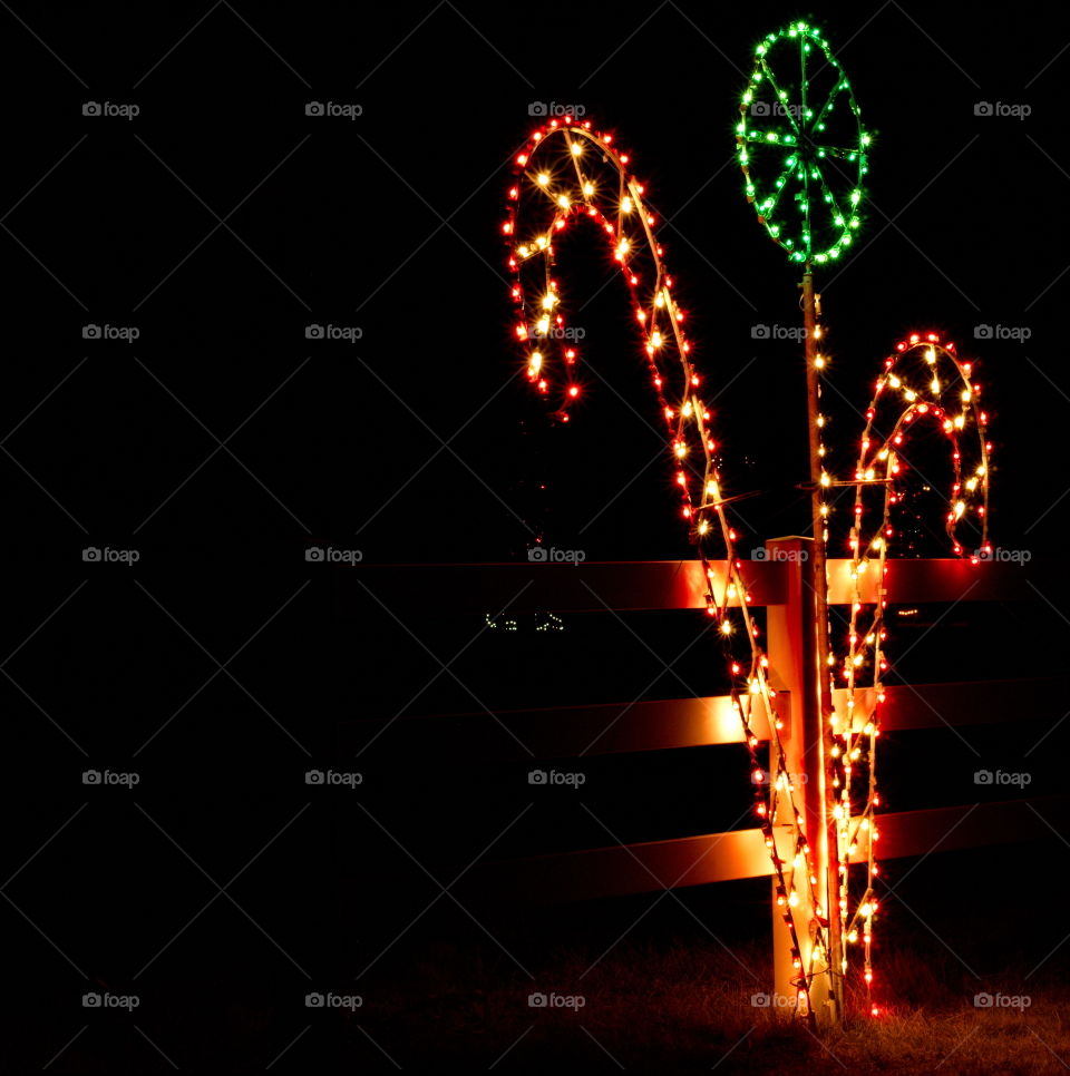 Candy Canes and lollipops made from colorful Christmas lights decorate a fence in Central Oregon. 