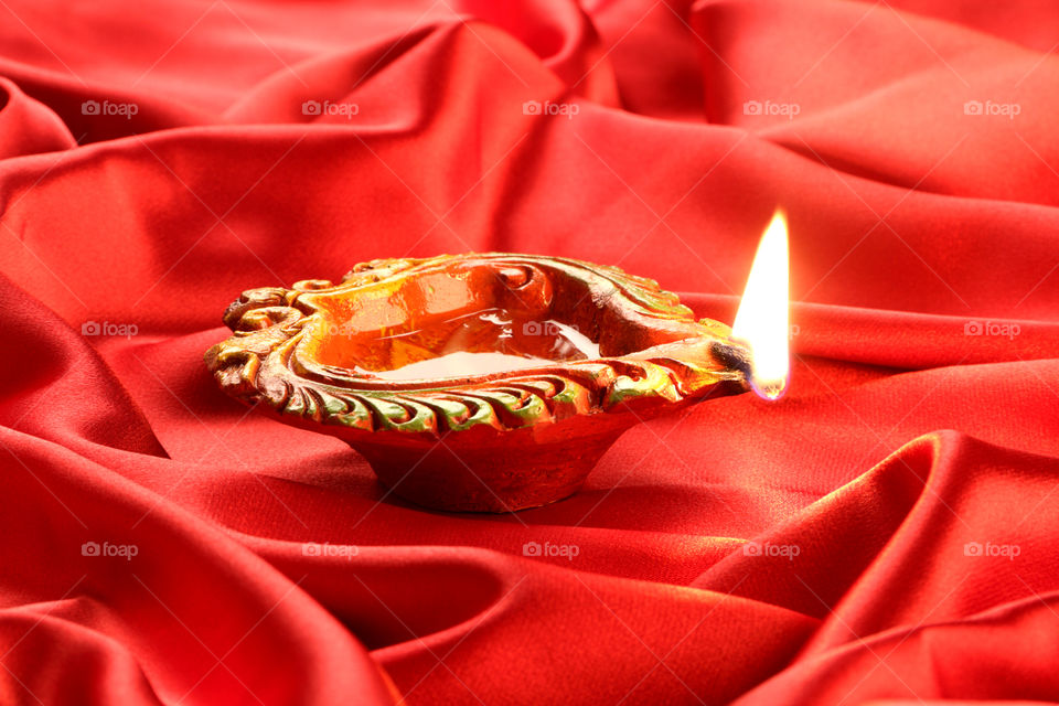 Indian festival Diwali diya oil lamp on red satin background