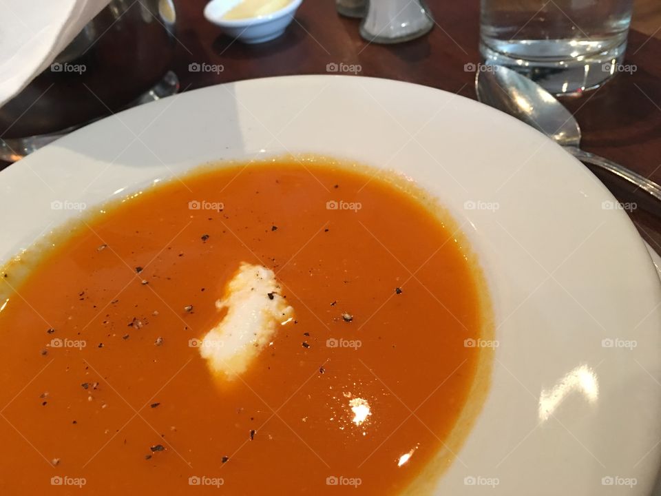 High angle view of orange coloured cold carrot soup with yogurt healthy lifestyle and eating photography high angle view on wood table with spoon 